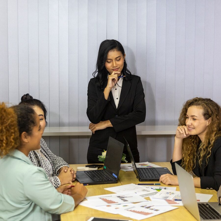 An Asian business lady leading a meeting with other coworkers. Business women from different ethnic races and cultures working together in an office for business development or plan